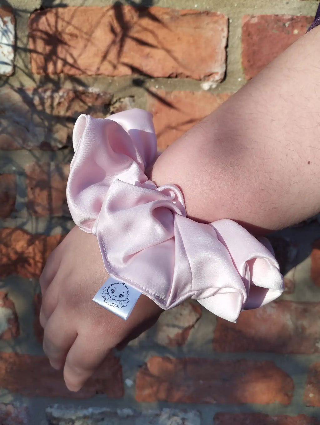 Blush Pink satin Jumbo scrunchie worn on a wrist to show its size