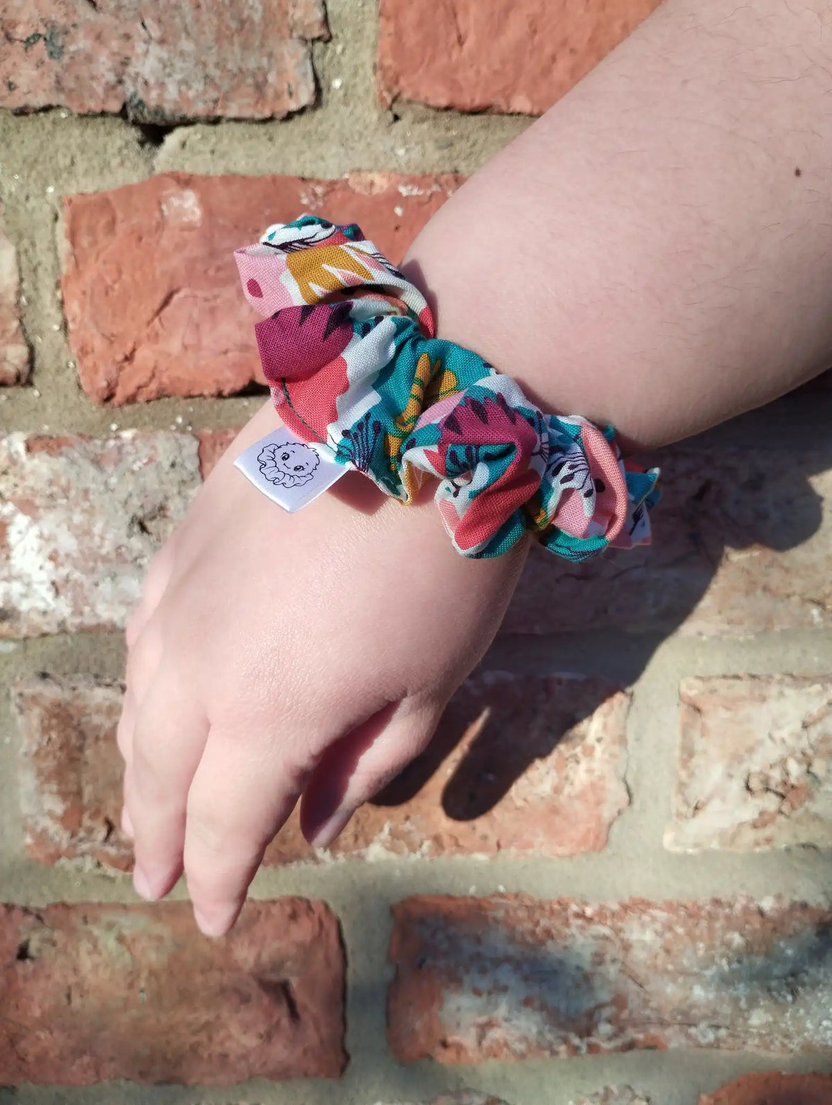 Carnival Bloom cotton Medium scrunchie worn on a wrist to show its size