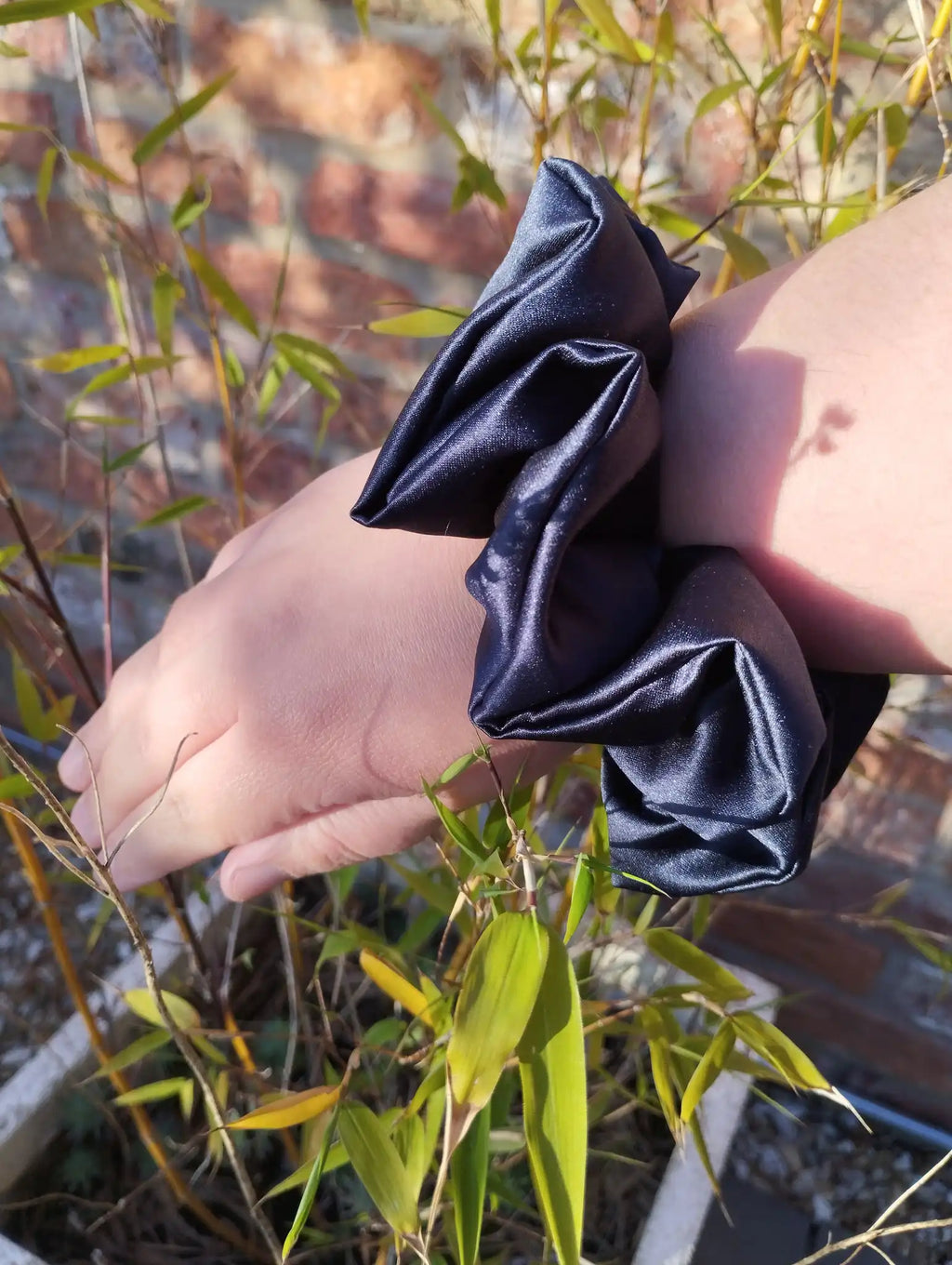 Inkwell Dark Navy satin Jumbo scrunchie worn on a wrist to show its size