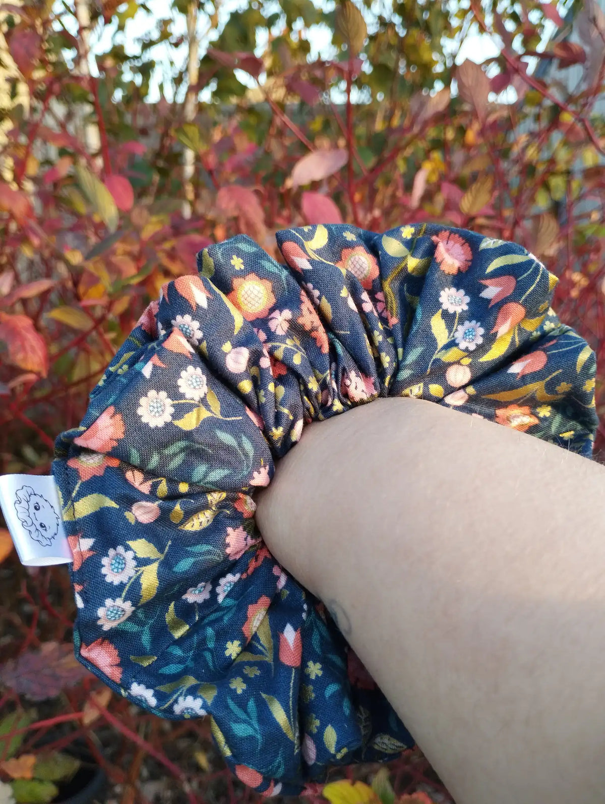 Navy Posy Jumbo Scrunchie worn on a wrist to show its size