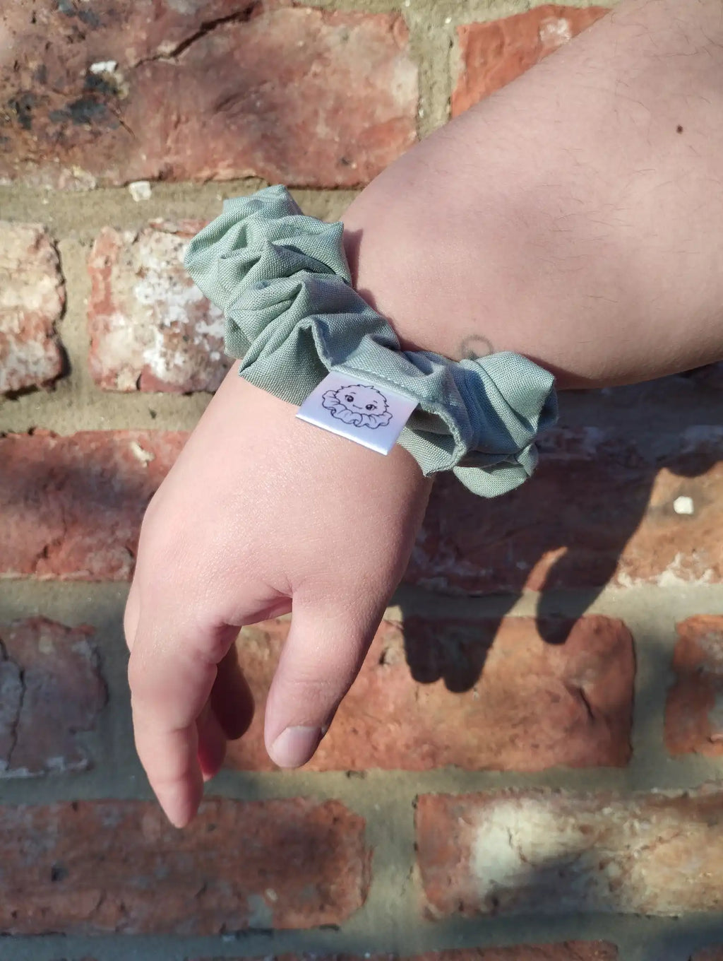 Sage Green cotton Medium scrunchie worn on a wrist to show its size