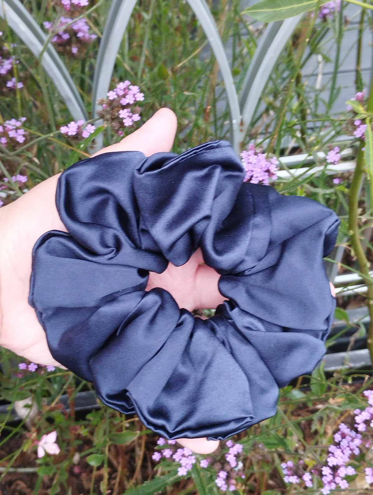 Midnight navy blue jumbo satin scrunchie held in a hand