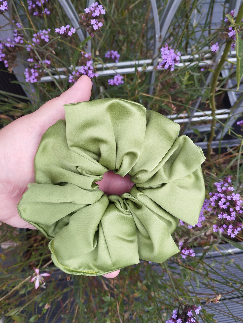 Moss green jumbo satin scrunchie held in a hand