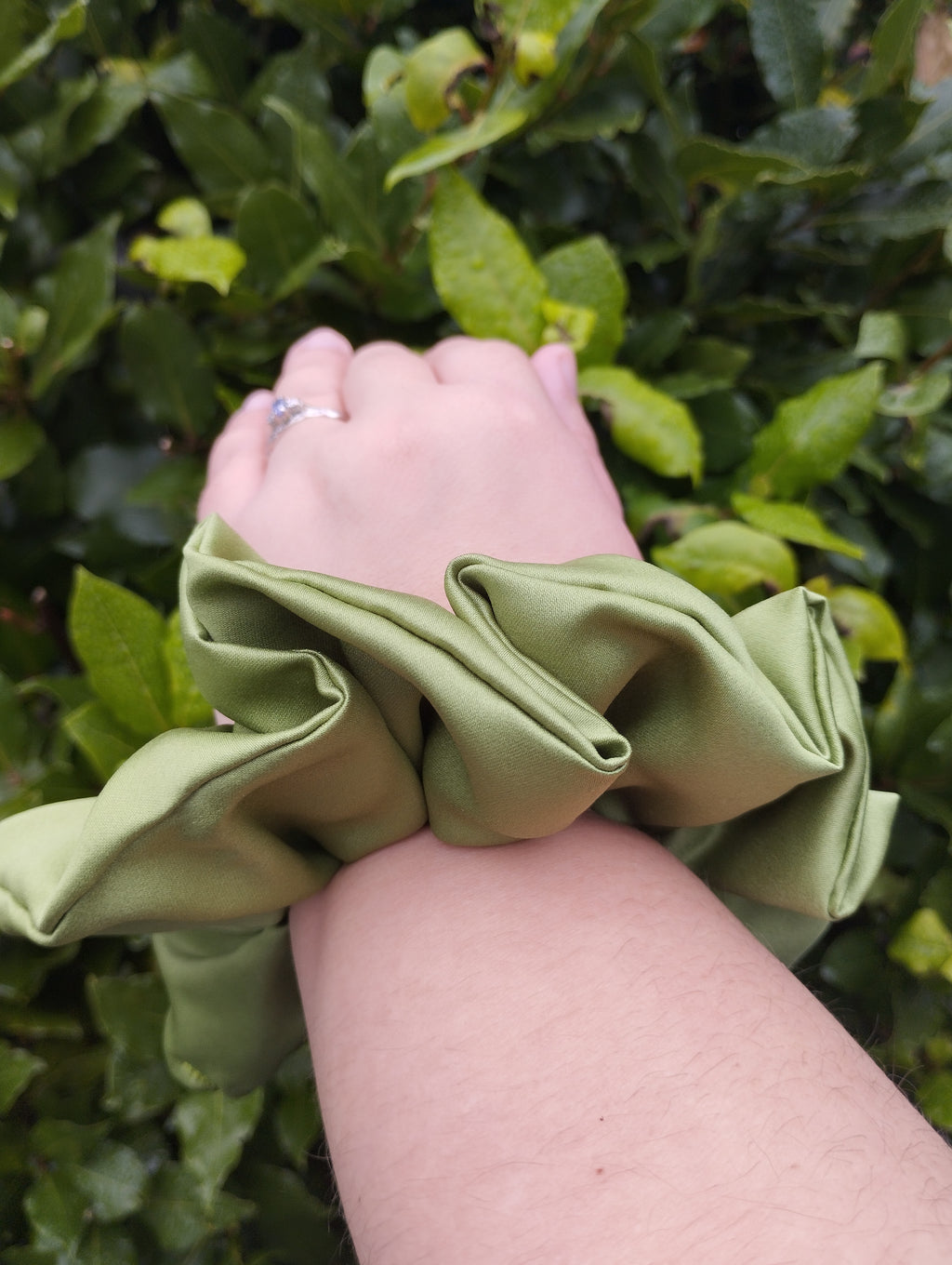Moss green jumbo satin scrunchie worn on a wrist