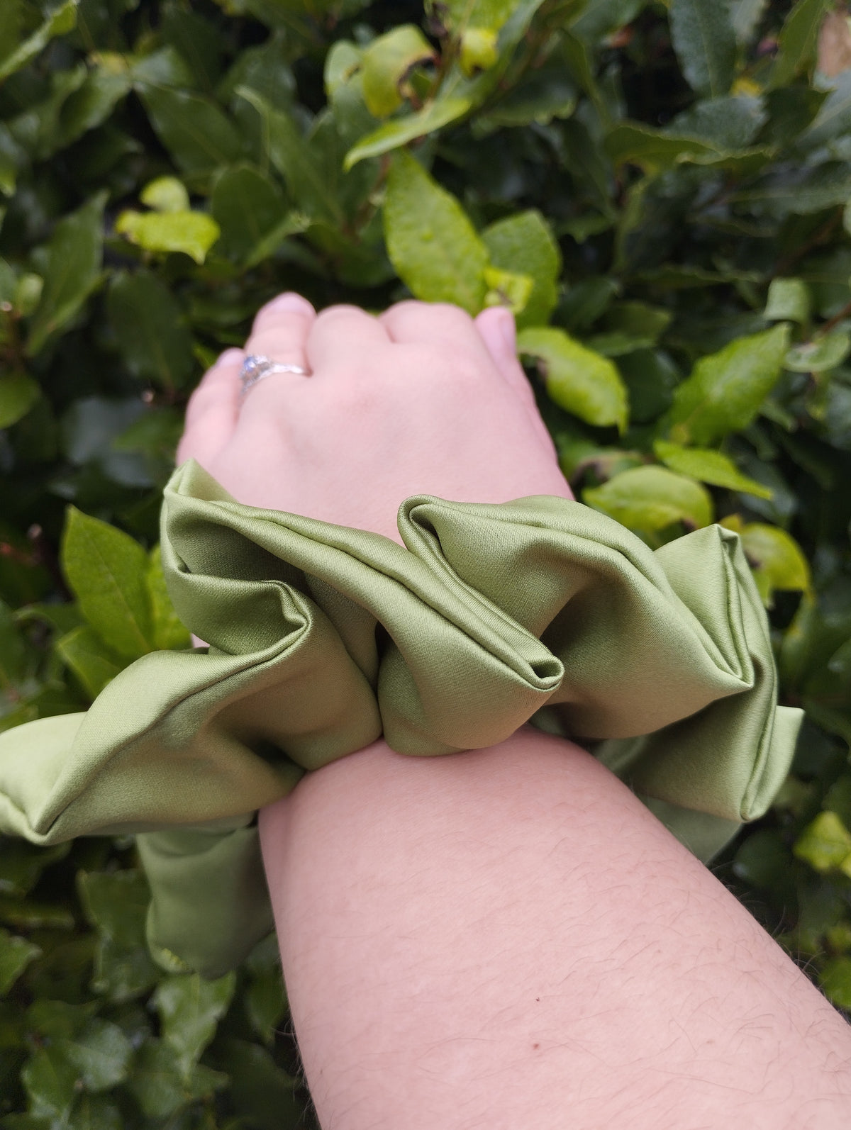 Moss green jumbo satin scrunchie worn on a wrist