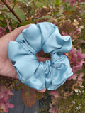 October Sky light blue jumbo satin scrunchie held in a hand