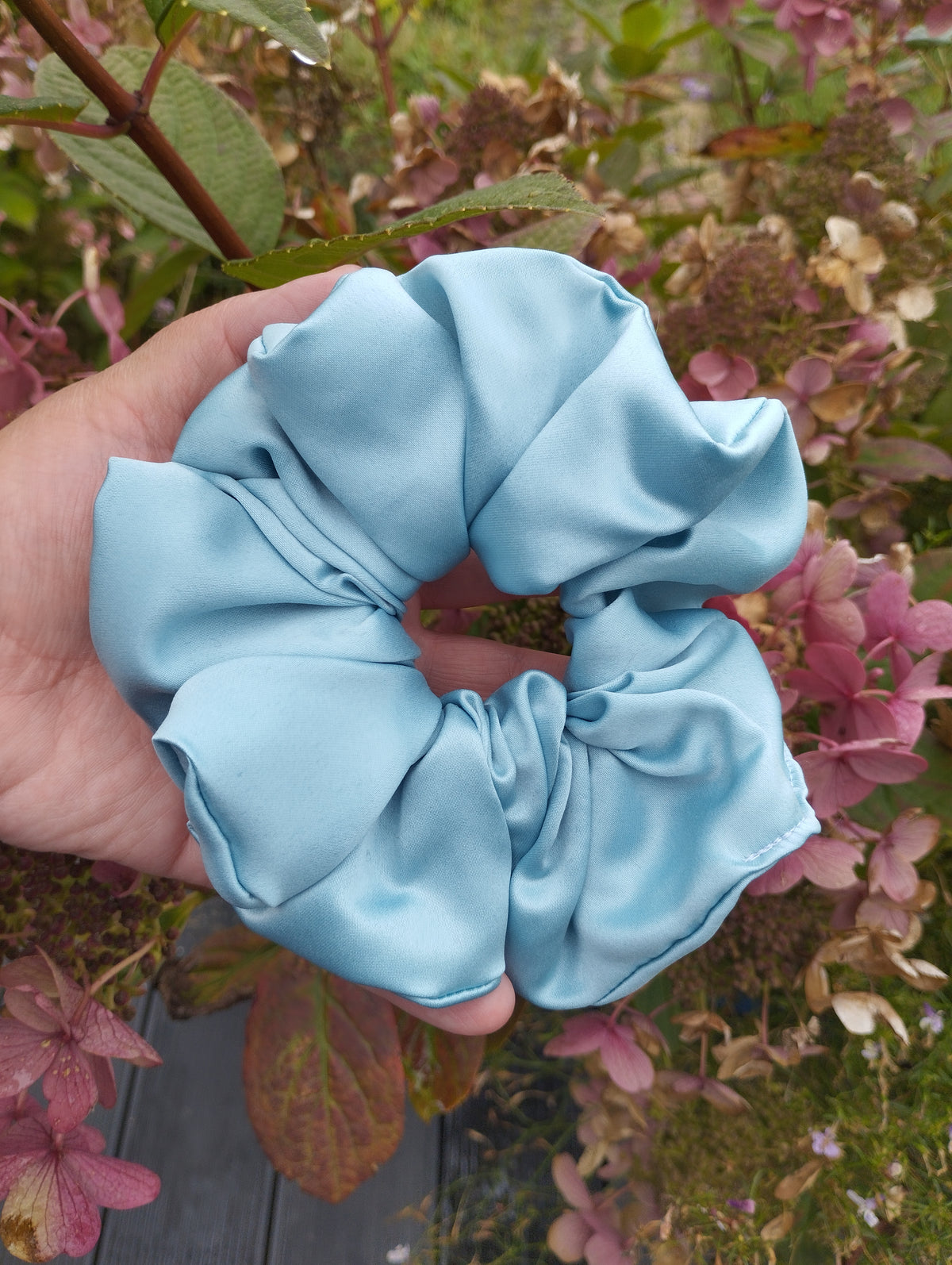 October Sky light blue jumbo satin scrunchie held in a hand
