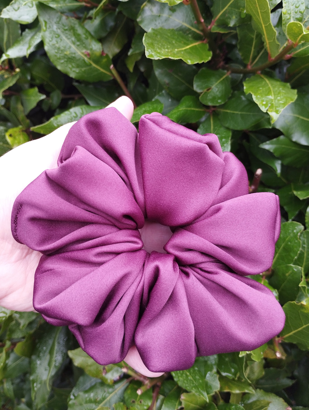 Ruby burgundy jumbo satin scrunchie held in a hand