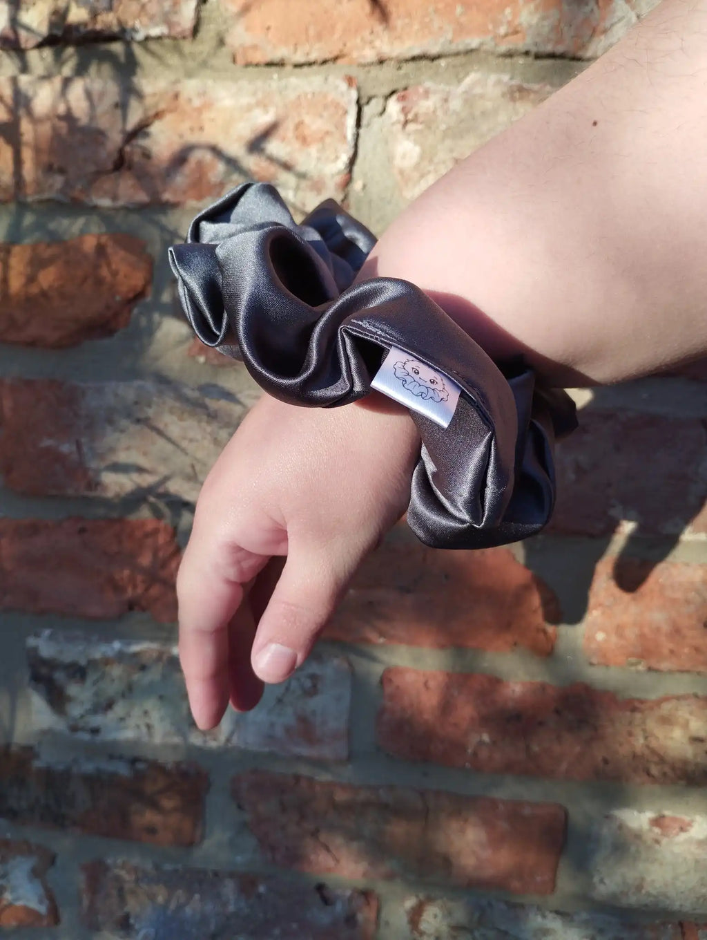 Slate Grey satin Jumbo scrunchie worn on a wrist to show its size