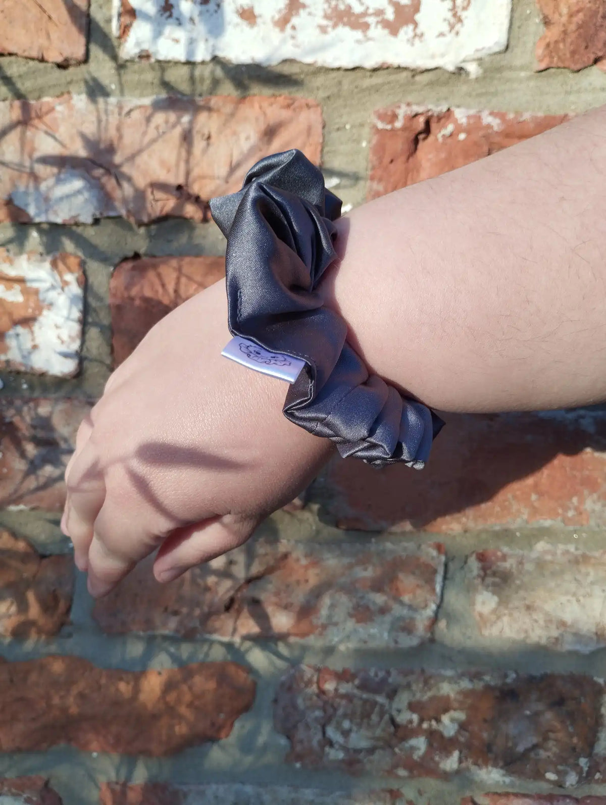 Slate Grey satin Medium scrunchie worn on a wrist to show its size