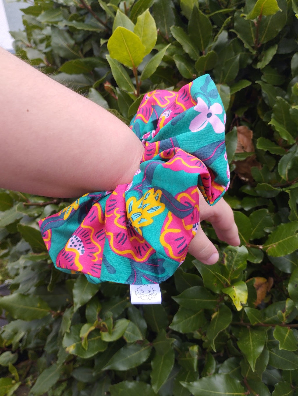 Tropical Bloom oversized floral scrunchie worn on a wrist to show its size