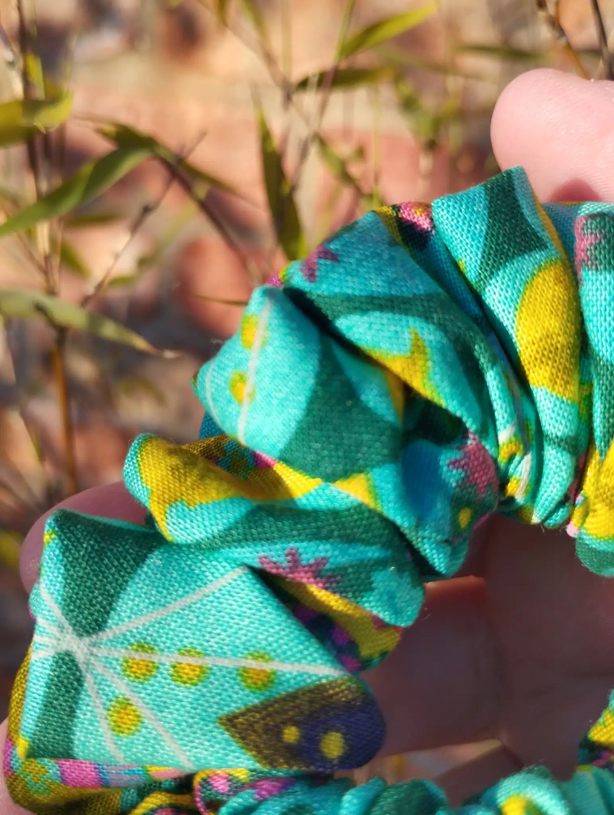 Close-up of the turquoise with yellow, pink and purple cotton fabric on Tropical Kaleidoscope Medium scrunchie
