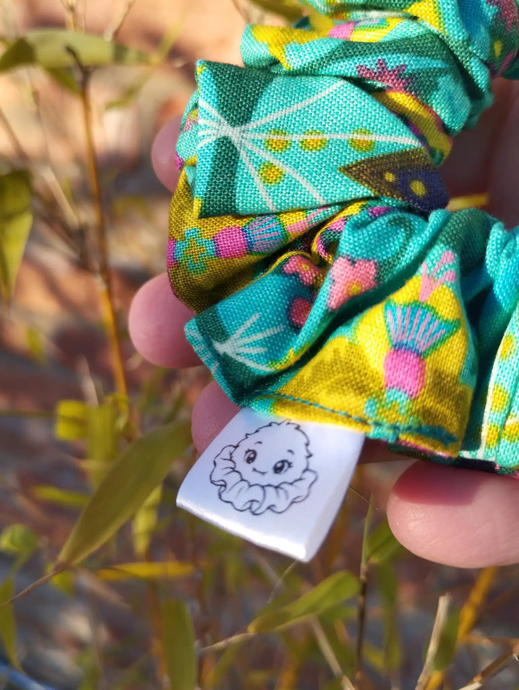Scrunchlings character label and stitching on Tropical Kaleidoscope cotton Medium scrunchie