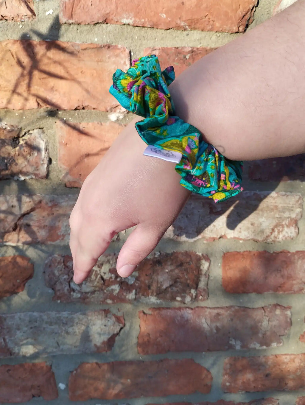 Tropical Kaleidoscope cotton Medium scrunchie worn on a wrist to show its size