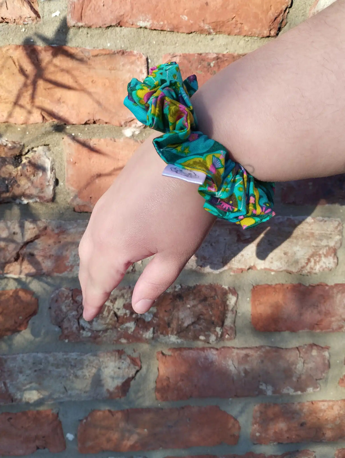 Tropical Kaleidoscope cotton Medium scrunchie worn on a wrist to show its size