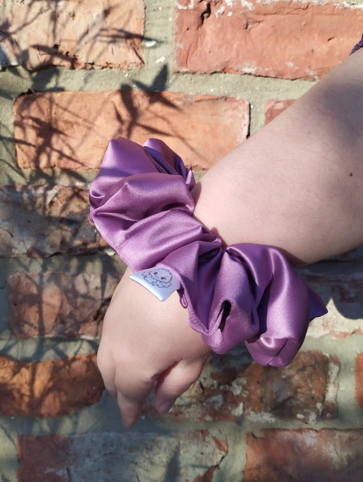 Wild Plum satin Jumbo scrunchie worn on a wrist to show its size